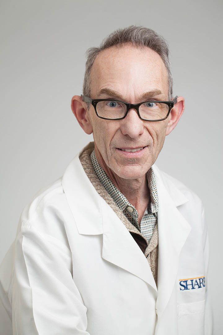 Doctor smiling in a white coat, arms crossed.
