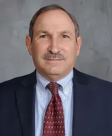 Smiling man in a suit against a white background.