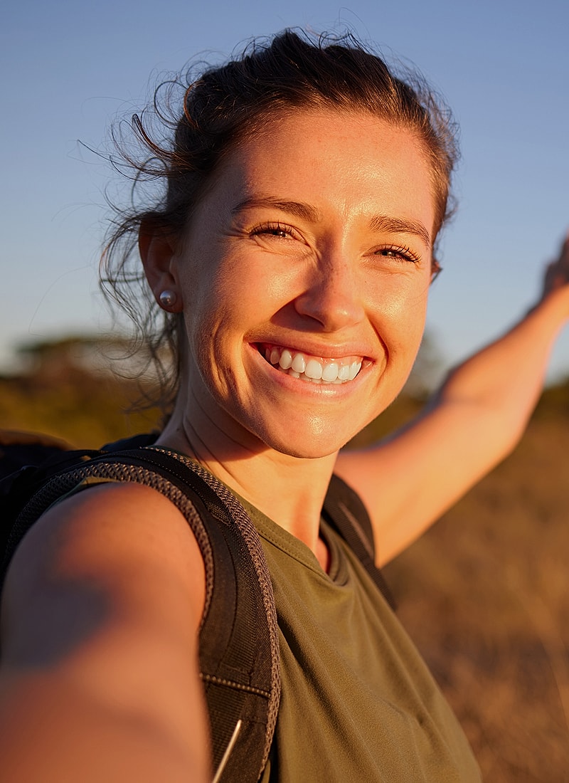 Smiling woman enjoying outdoor adventure at sunset.