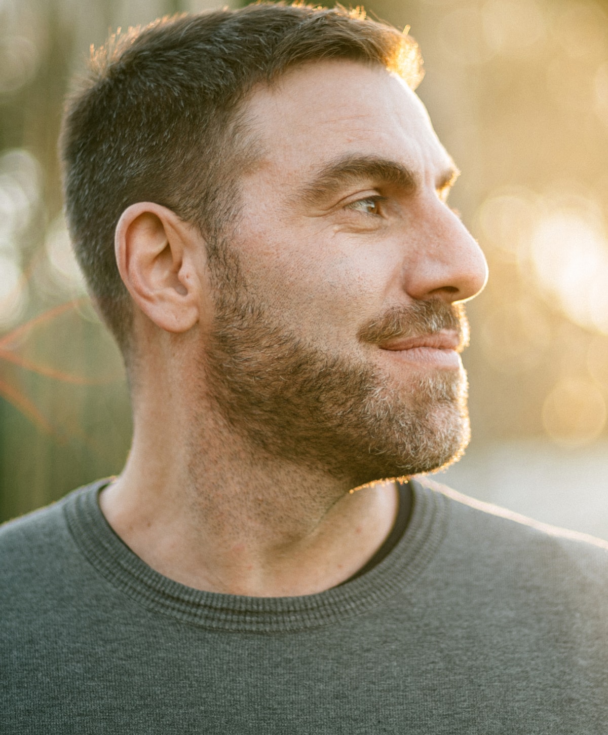 Man smiling in natural light with soft background.