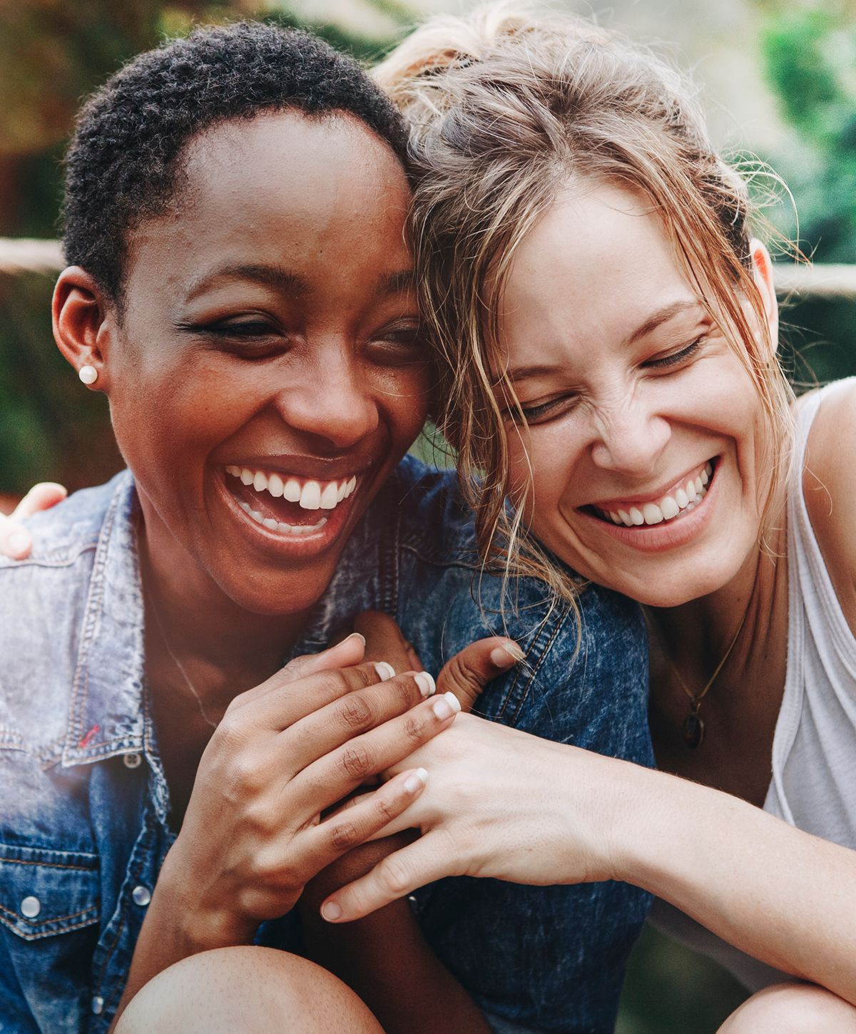 Two friends laughing together outdoors.