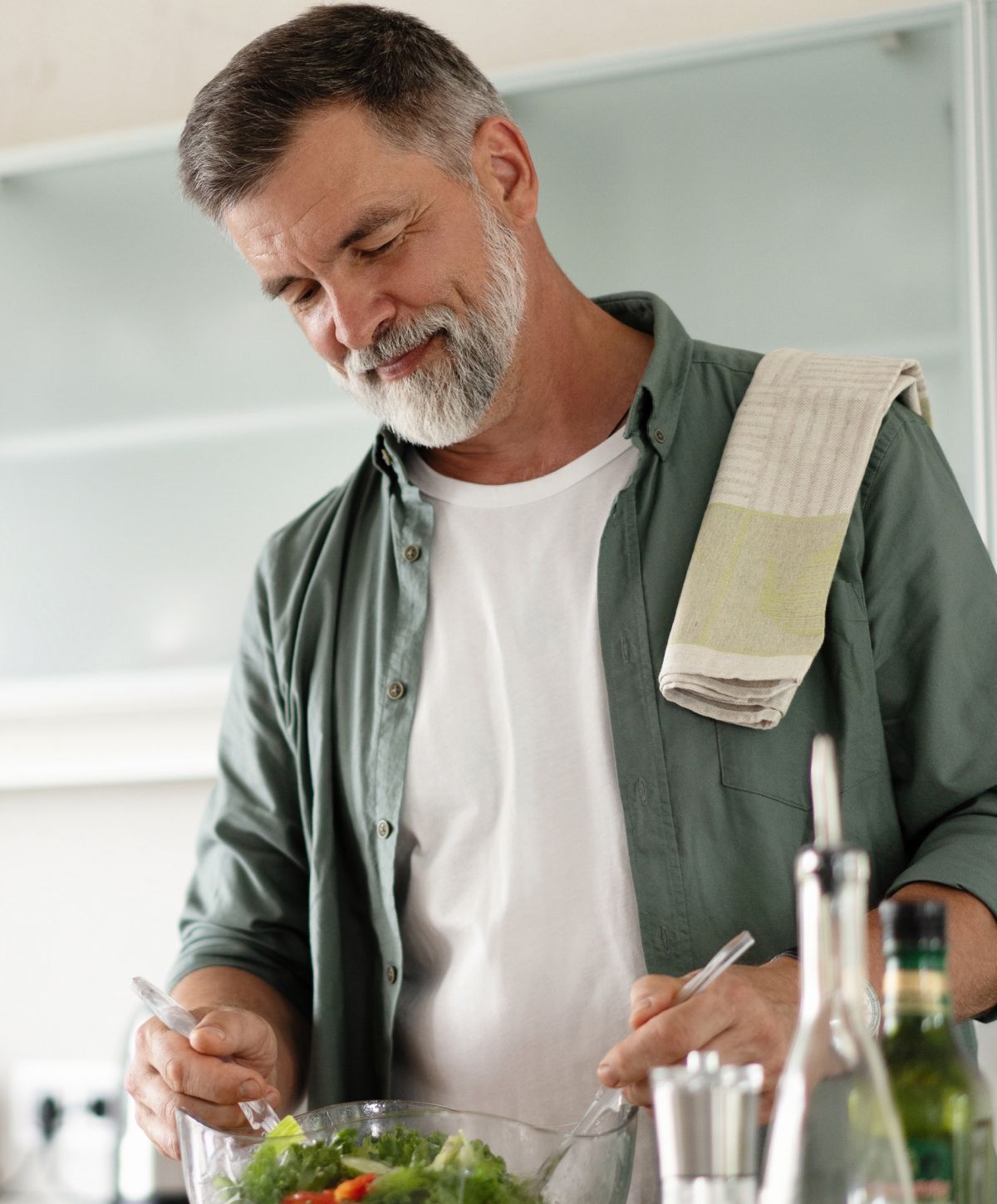 Man preparing a fresh salad in kitchen.