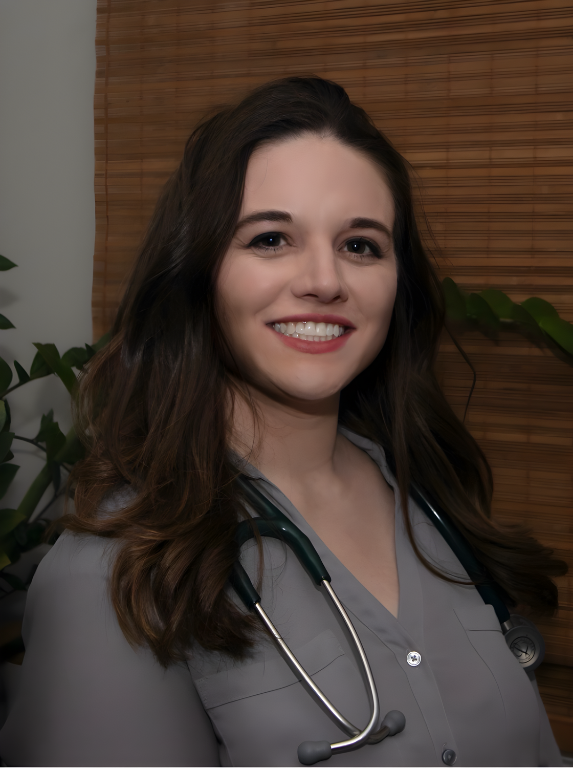 Woman smiling in floral shirt against plain background.