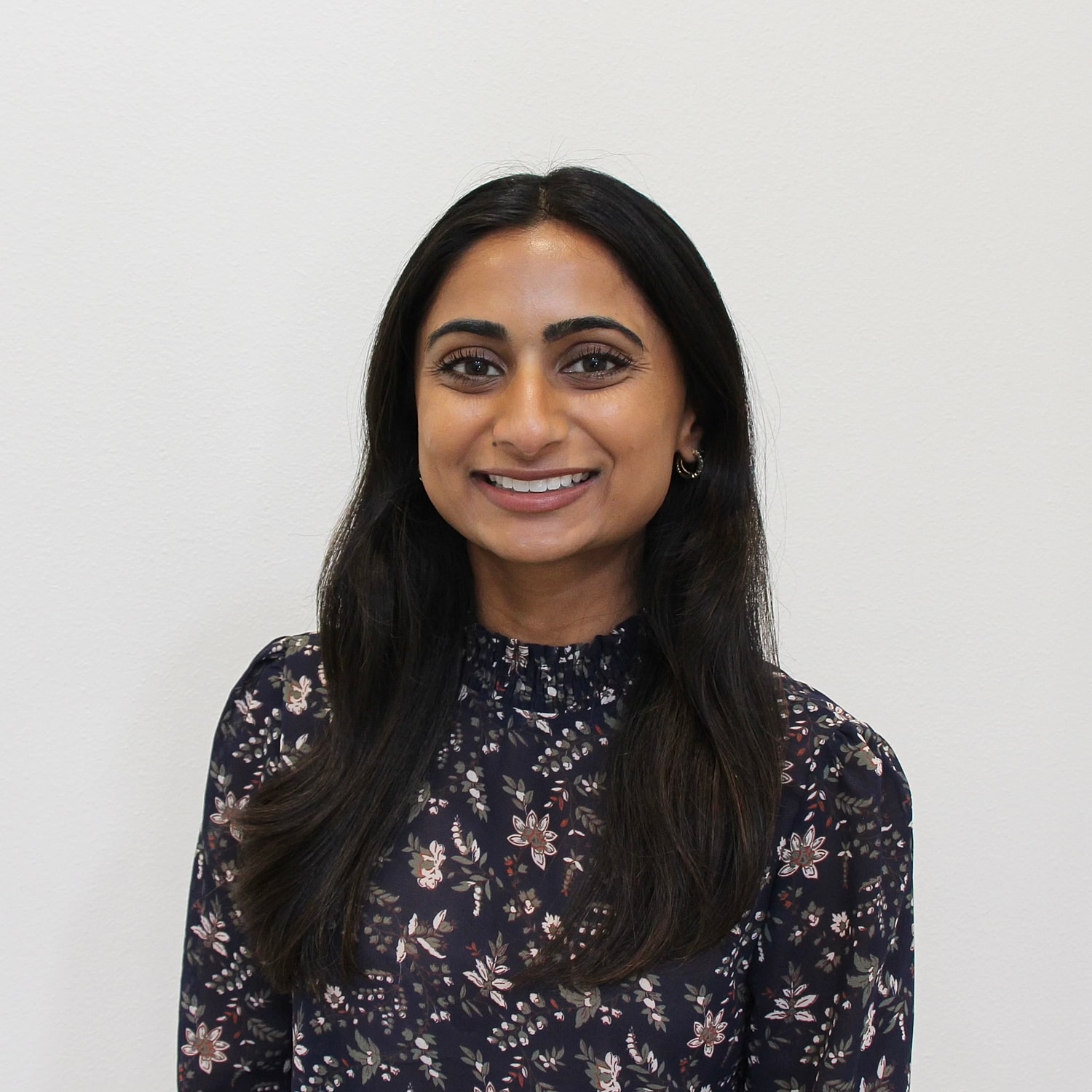 Smiling woman in floral blouse against white background.