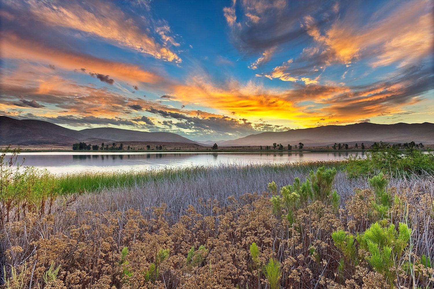 Vibrant sunset over serene lake and mountains.