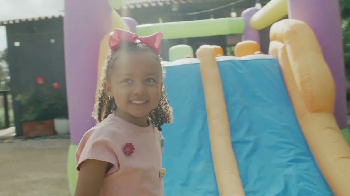 Smiling child near colorful inflatable slide.