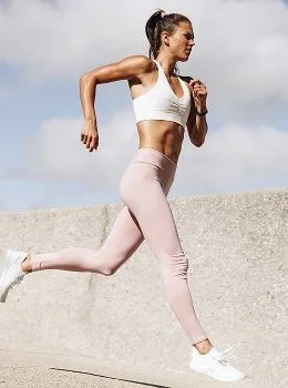 Woman running in stylish athletic wear outdoors.