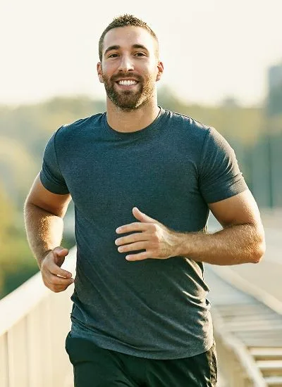Smiling man jogging outdoors on sunny day