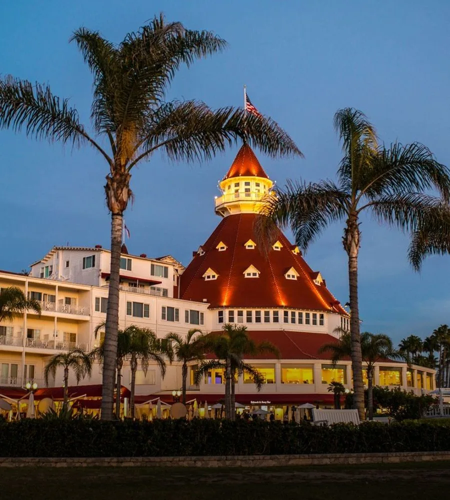 Historic hotel with palm trees at sunset.