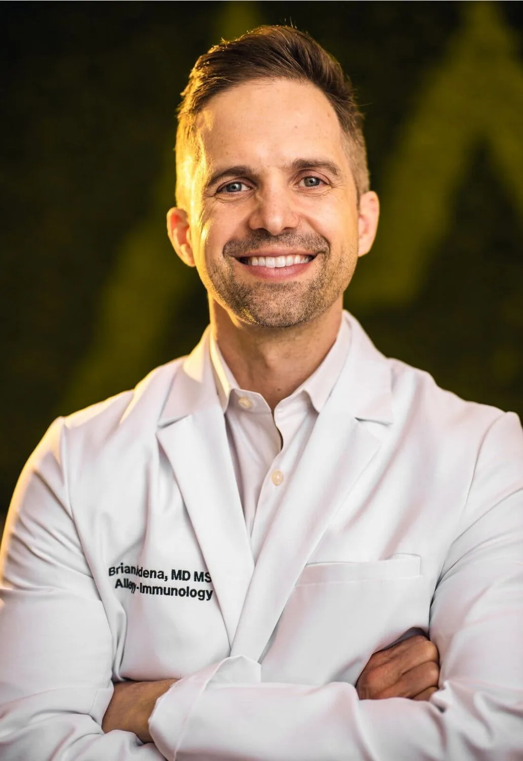 Smiling doctor in white coat with crossed arms.