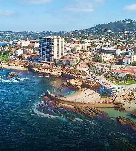 Coastal cityscape with buildings and rocky shoreline.