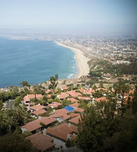 Coastal cityscape with buildings and rocky shoreline.