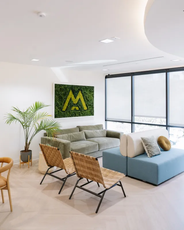 Main waiting lounge with the Modena living-logo wall at the Solana Beach office.