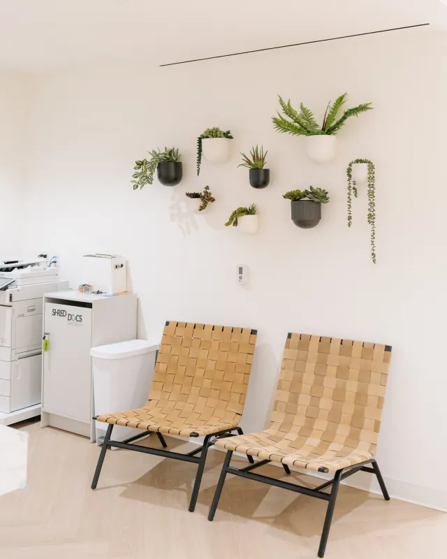 Waiting chairs beneath a wall display of plants at the Solana Beach office.
