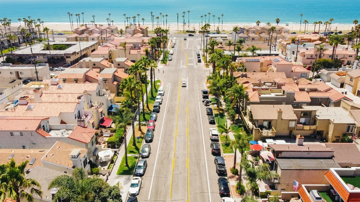 Aerial view of Huntington Beach homes, palm trees, and the Pacific Ocean.