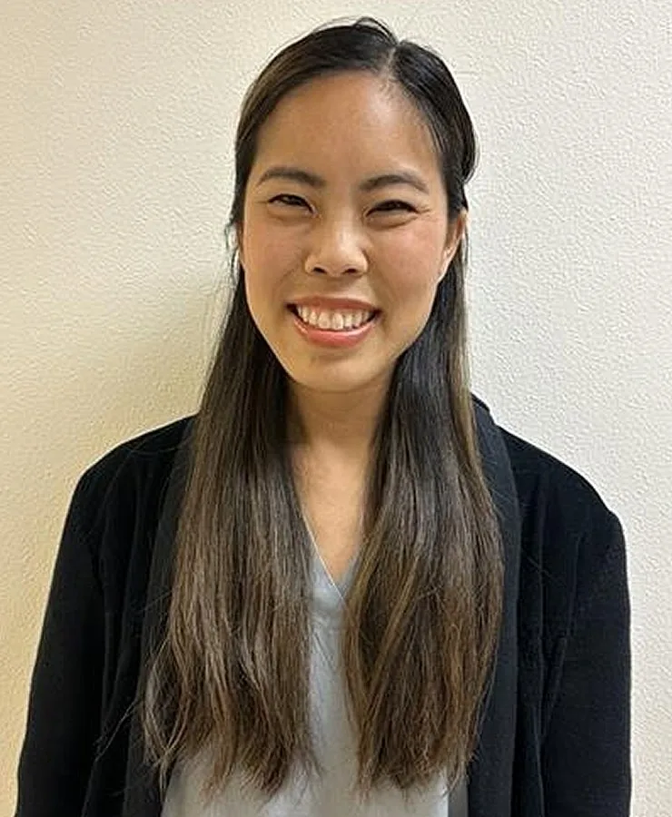 Smiling woman with long hair against plain background.