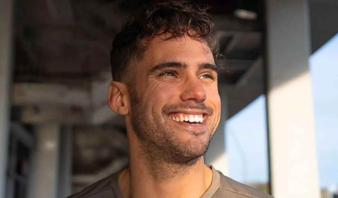 Smiling man in casual attire, natural light.