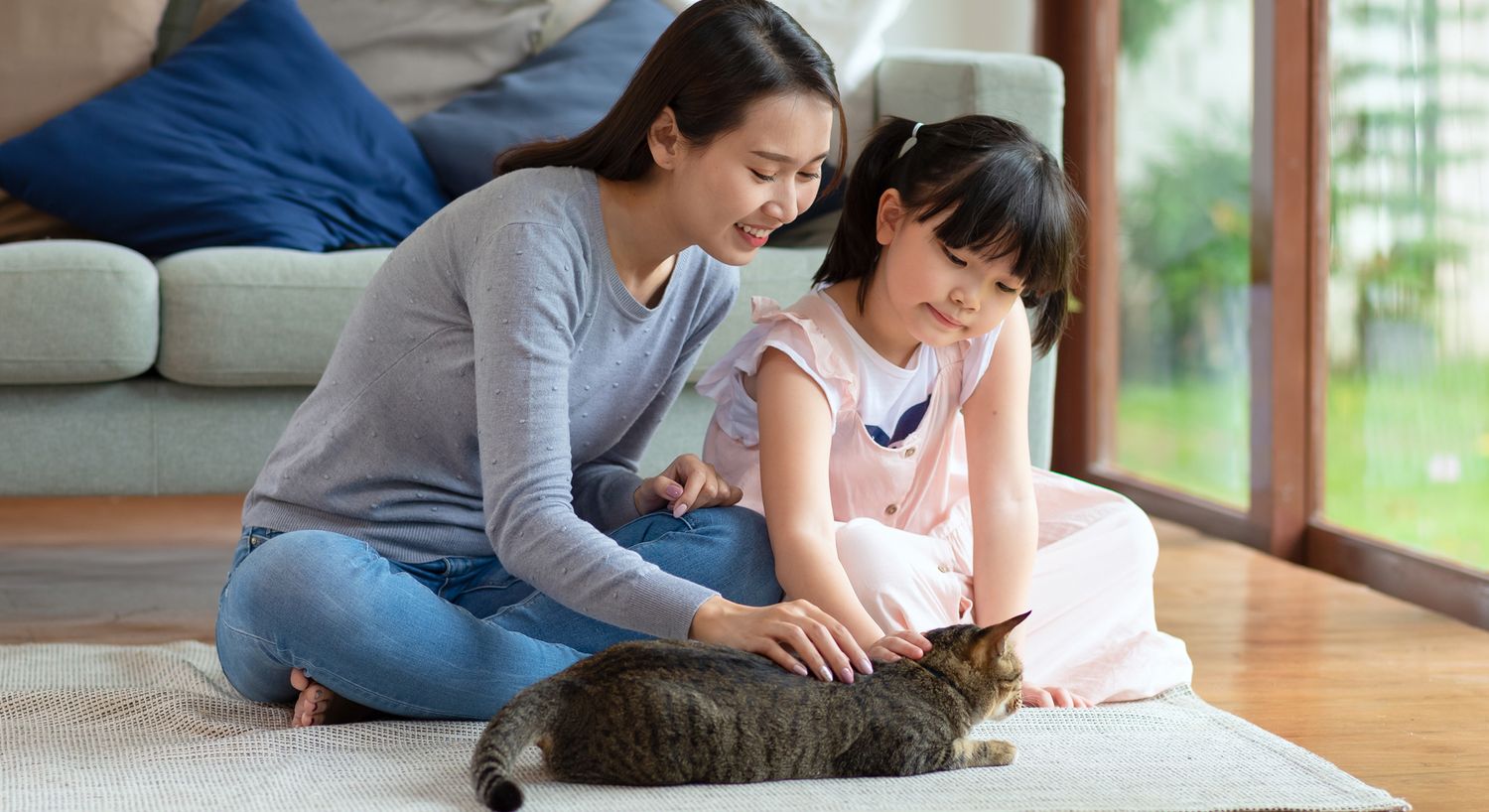 Mother and daughter spending time with a cat.